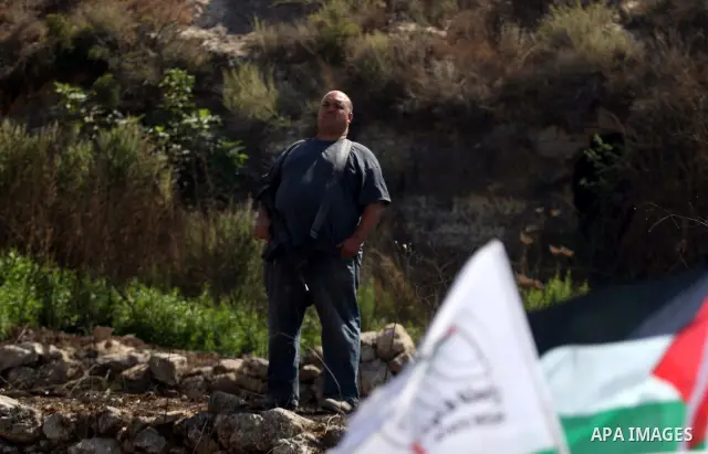 An armed Israeli settler from the Halamish settlement looks at members of pro-Palestinian volunteer-based campaign which will intervene and respond to cases of violence towards Palestinians by Jewish settlers in the West...