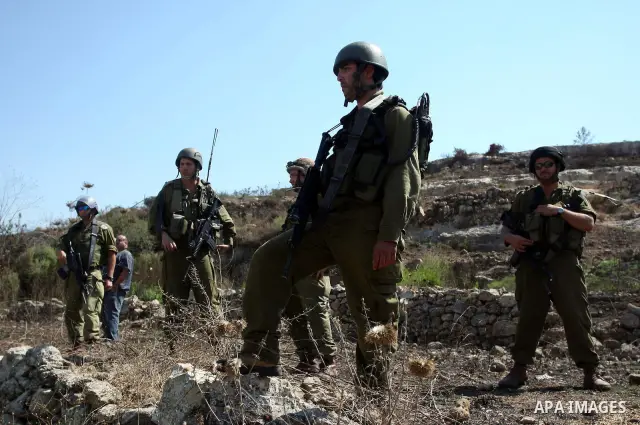 Israeli soldiers stand guard in front of members pro-Palestinian volunteer-based campaign (not seen) which will intervene and respond to cases of violence towards Palestinians by Jewish settlers in the West Bank, in the...