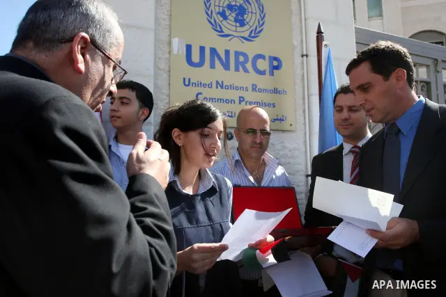 Palestinian school girl, left, hands a letter, addressed to the United Nations Secretary-General Ban Ki-moon, to UN officer Pascale Soto, right, during a rally to support the Palestinian statehood bid in the United Natio...