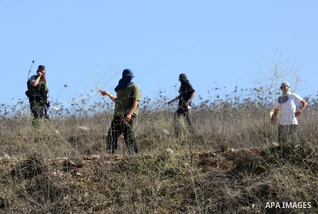 Masked Jewish settlers throw stones toward Palestinians in the West Bank village of Assira al-Kibliya, near Nablus Tuesday, Sept. 20, 2011. Israeli settlers and Palestinian villagers threw stones at each other Tuesday, a...