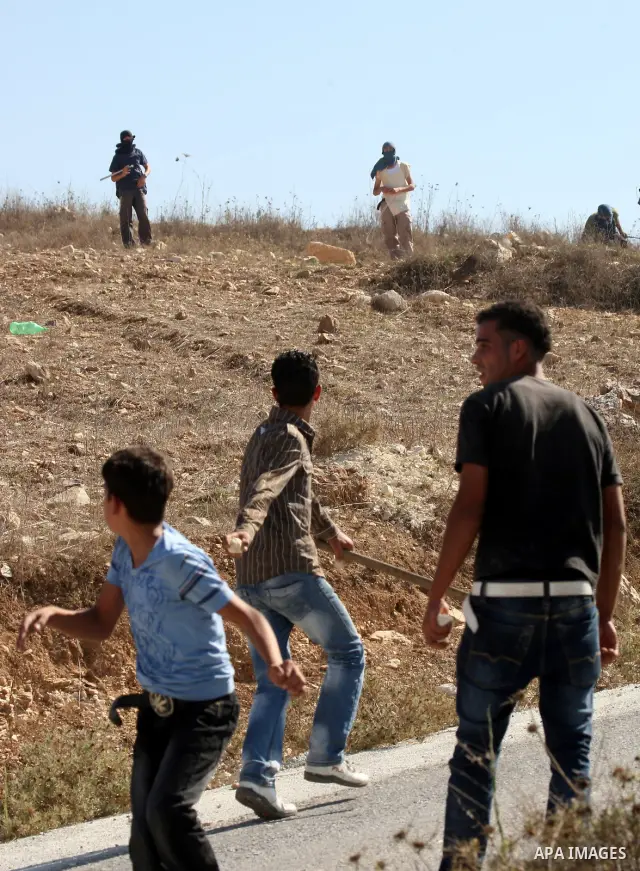 Palestinian youths throw stones toward Jewish settlers in the West Bank village of Assira al-Kibliya, near Nablus Tuesday, Sept. 20, 2011. Israeli settlers and Palestinian villagers threw stones at each other Tuesday, a...