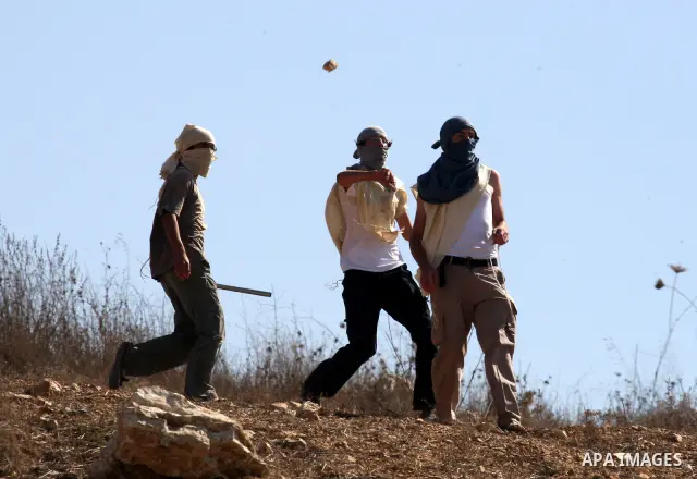 Masked Jewish settlers throw stones toward Palestinians in the West Bank village of Assira al-Kibliya, near Nablus Tuesday, Sept. 20, 2011. Israeli settlers and Palestinian villagers threw stones at each other Tuesday, a...