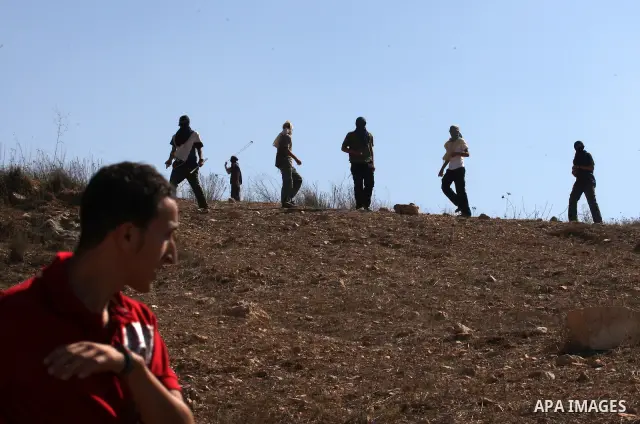 Masked Jewish settlers throw stones toward Palestinians in the West Bank village of Assira al-Kibliya, near Nablus Tuesday, Sept. 20, 2011. Israeli settlers and Palestinian villagers threw stones at each other Tuesday, a...