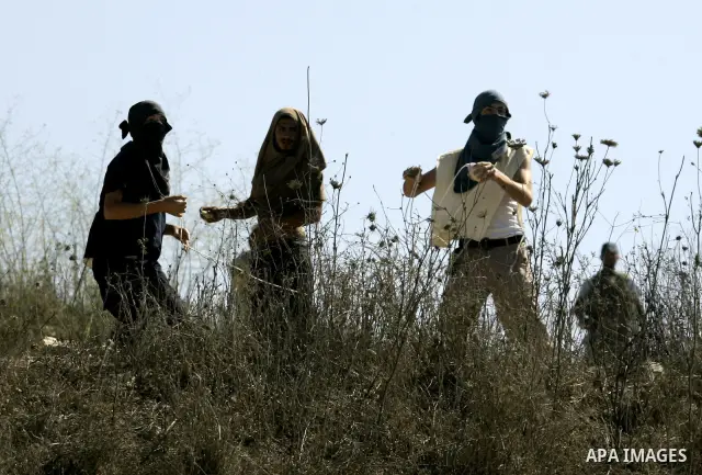 Masked Jewish settlers throw stones toward Palestinians in the West Bank village of Assira al-Kibliya, near Nablus Tuesday, Sept. 20, 2011. Israeli settlers and Palestinian villagers threw stones at each other Tuesday, a...