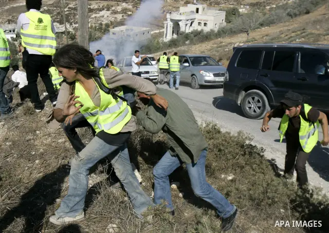 Teargas envelops Palestinians during clashes with Israeli troops in the West Bank village of Assira al-Kibliya, Tuesday, Sept. 20, 2011. Israeli settlers and Palestinian villagers threw stones at each other Tuesday, a da...