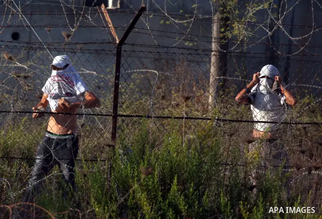 Masked Jewish settler boys from the Israeli West bank settlement of Bet El, throw stones at Palestinians Near the refugee camp of Jalazoun in the West Bank city of Ramallah on September 20, 2011. Reports state that Pales...