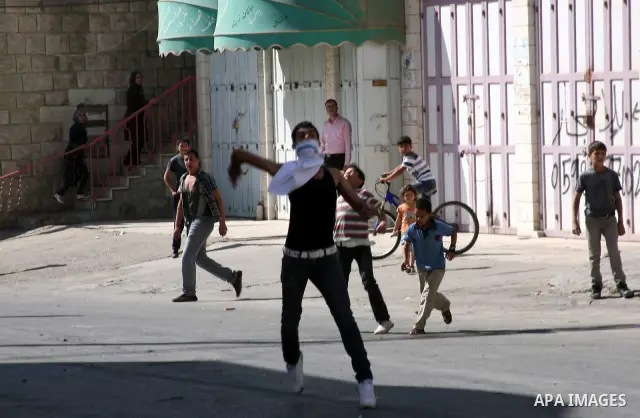 Palestinian youths throw stones towards Israeli soldiers during a protest in the West Bank city of Hebron 21 September 2011, as Palestinian president Mahmud Abbas prepares to submit a formal request for Palestine to beco...