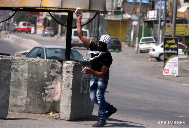 A Palestinian protester throws stones at Israeli soldiers during clashes at the Qalandia checkpoint between the West Bank city of Ramallah and Jerusalem, Wednesday, Sept. 21, 2011. Palestinians clashed with Israeli secur...
