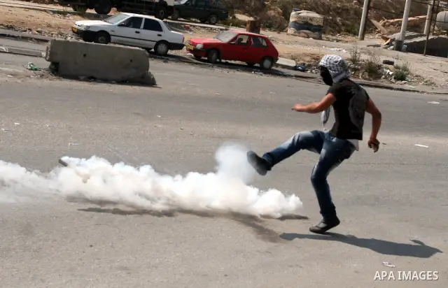 A Palestinian protester kicks atear gas canister at Israeli soldiers during clashes at the Qalandia checkpoint between the West Bank city of Ramallah and Jerusalem, Wednesday, Sept. 21, 2011. Palestinians clashed with Is...