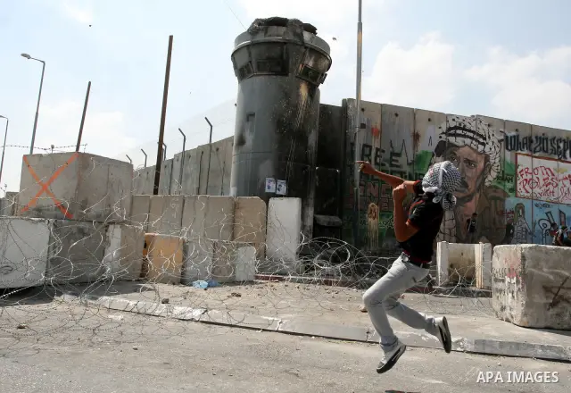 A Palestinian protester throws stones at Israeli soldiers during clashes at the Qalandia checkpoint between the West Bank city of Ramallah and Jerusalem, Wednesday, Sept. 21, 2011. Palestinians clashed with Israeli secur...