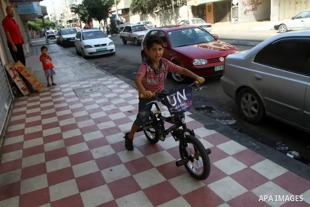 A Palestinian boy rides a bicycle decorated with a sign supporting the Palestinians' bid in the United Nations for statehood recognition, on September 23, 2011 in Gaza City. Palestinian president Mahmud Abbas will presen...