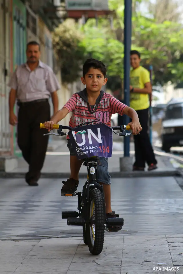A Palestinian boy rides a bicycle decorated with a sign supporting the Palestinians' bid in the United Nations for statehood recognition, on September 23, 2011 in Gaza City. Palestinian president Mahmud Abbas will presen...