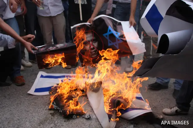 Palestinian protesters burn an Israeli flag and a poster depicting U.S. President Barack Obama at a weekly protest in the West Bank village of Nabi Saleh, near Ramallah September 23, 2011. Israeli security forces were on...
