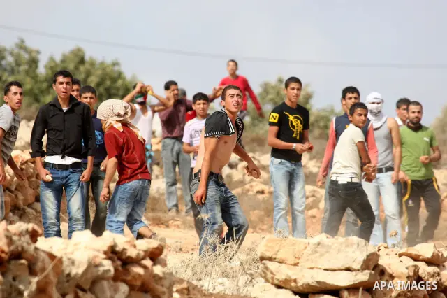 Palestinians throw stones toward Israeli troops during clashes in the West Bank village of Qusra, south of Nablus, on September 23, 2011. A Palestinian man was shot dead by Israeli troops in clashes which erupted after s...