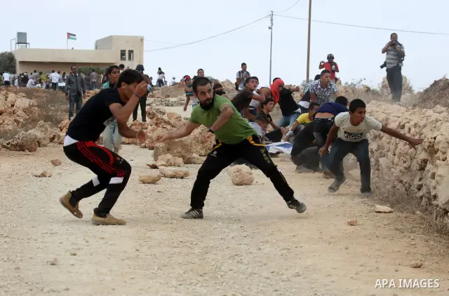 Palestinians throw stones toward Israeli troops during clashes in the West Bank village of Qusra, south of Nablus, on September 23, 2011. A Palestinian man was shot dead by Israeli troops in clashes which erupted after s...