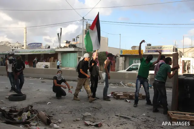 Palestinian men throw stones at Israeli soldiers during riots at the Qalandia checkpoint near Ramallah, on 23 September 2011. Reports state that Israeli security services were on high alert across the country, poised to...