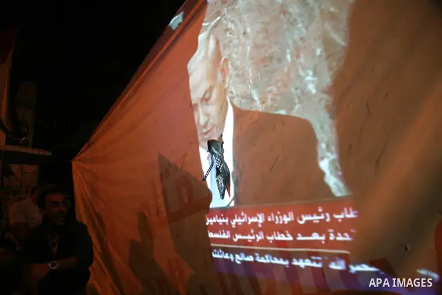 Palestinians hold up shoes as they watch a screen relaying live footage of Israeli Prime Minister Benjamin Netanyahu speech at the United Nations General Assembly in New York on September 23, 2011 in the West Bank city o...