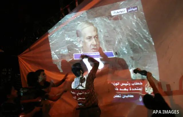 Palestinians hold up shoes as they watch a screen relaying live footage of Israeli Prime Minister Benjamin Netanyahu speech at the United Nations General Assembly in New York on September 23, 2011 in the West Bank city o...