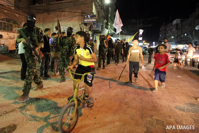 Palestinian militants of the Nabil Massud Unit of the Al-Aqsa Martyrs Brigades, an armed offshoot of the Fatah movement, march while the boys watch them, in the Jabalia refugee camp in the northern Gaza Strip on Sept. 28...