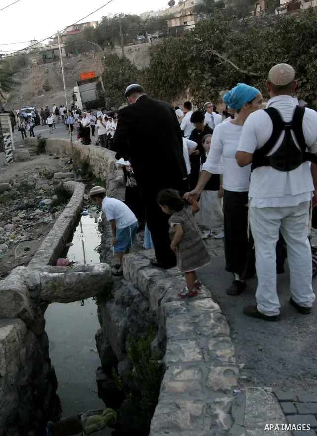 Jews gather to read prayers and perform 'Tashlich,' meaning to 'cast off,' near a small stream of water overlooking the arab East Jerusalem village of Silwan, at sun down on the first day of Jewish New Year, or Rosh Hash...