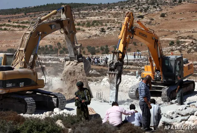 Israeli border police officers stand guard as demolition vehicles destroy a man-made reservoir on a Palestinian farm near the West Bank city of Hebron, on 04 October 2011. Reports state that tensions rose as Palestinian...