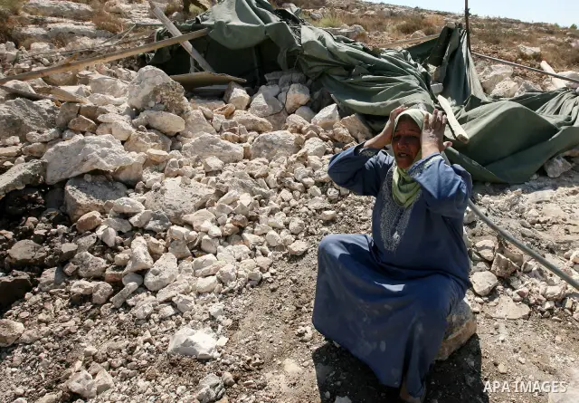 A Palestinian woman reacts as demolition vehicles destroy a man-made reservoir on a Palestinian farm near the West Bank city of Hebron, on 04 October 2011. Reports state that tensions rose as Palestinian homes were destr...