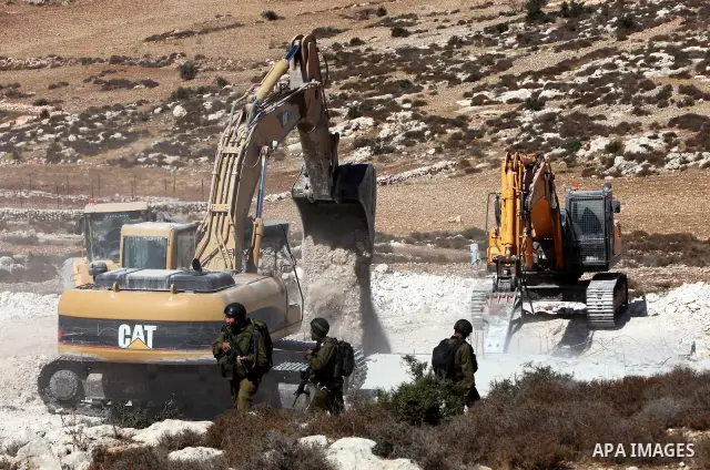 Israeli border police officers stand guard as demolition vehicles destroy a man-made reservoir on a Palestinian farm near the West Bank city of Hebron, on 04 October 2011. Reports state that tensions rose as Palestinian...