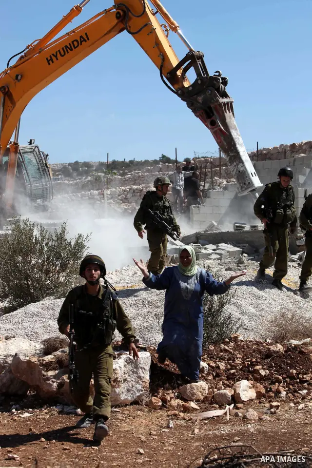 Israeli border police officers stand guard as demolition vehicles destroy a man-made reservoir on a Palestinian farm near the West Bank city of Hebron, on 04 October 2011. Reports state that tensions rose as Palestinian...