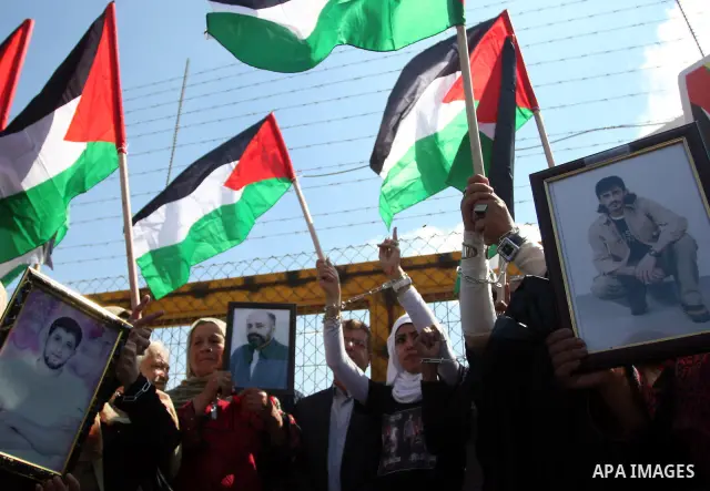 Palestinian protestors wave their national flag and shout slogans during a demonstration calling for the release of prisoners held in Israeli jails and in support of inmates in hunger strike, on October 5, 2011 near Isra...