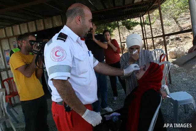 A Palestinian paramedic helps a woman after Israeli soldiers fire tear gas toward protestors during a demonstration calling for the release of prisoners held in Israeli jails and in support of inmates in hunger strike, o...