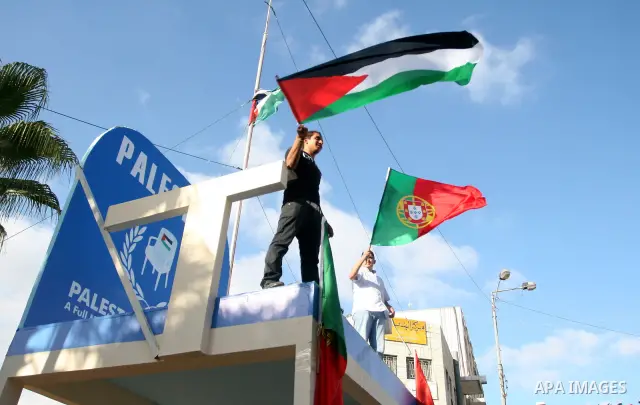 Palestinians wave their national flag and Portugal flag as they celebrate the National Day of Portugal in the West Bank city of Ramallah October 6, 2011. Palestinians have demanded the State of Portugal to vote for the r...