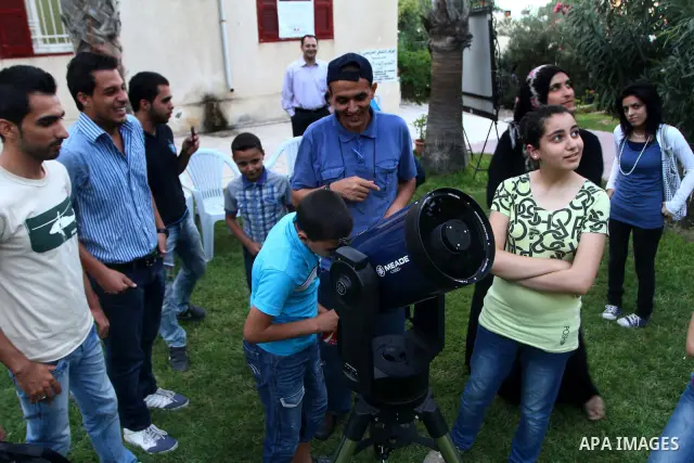 Palestinians look at the moon through a small telescope brought into Gaza City by the French Cultural Center (CCF) on Oct, 6, 2011. The CCF gave Gazan children and youths the opportunity to look at the stars and planets...