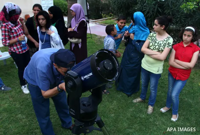Palestinians look at the moon through a small telescope brought into Gaza City by the French Cultural Center (CCF) on Oct, 6, 2011. The CCF gave Gazan children and youths the opportunity to look at the stars and planets...
