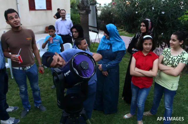 Palestinians look at the moon through a small telescope brought into Gaza City by the French Cultural Center (CCF) on Oct, 6, 2011. The CCF gave Gazan children and youths the opportunity to look at the stars and planets...