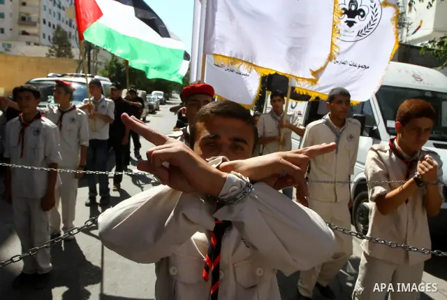 Palestinian scouts stand during Friday prayer next to the Red Cross building in Gaza City as they call for the release of Palestinian prisoners from Israeli jails and support of inmates in hunger strike on October 7, 201...