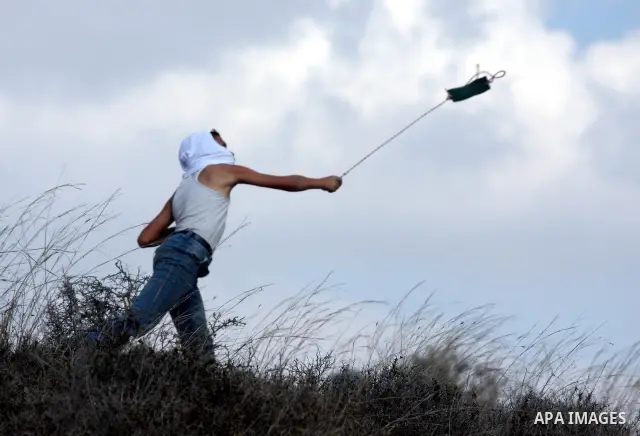 A Palestinian youth uses a sling to hurl stones towards Israeli soldiers during a weekly demonstration against Israeli settlement expansion, in the West Bank village of Nabi Saleh, on October 7, 2011. Photo by Issam Rima...