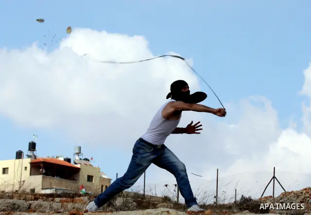 A Palestinian youth uses a sling to hurl stones towards Israeli soldiers during a weekly demonstration against Israeli settlement expansion, in the West Bank village of Nabi Saleh, on October 7, 2011. Photo by Issam Rima...