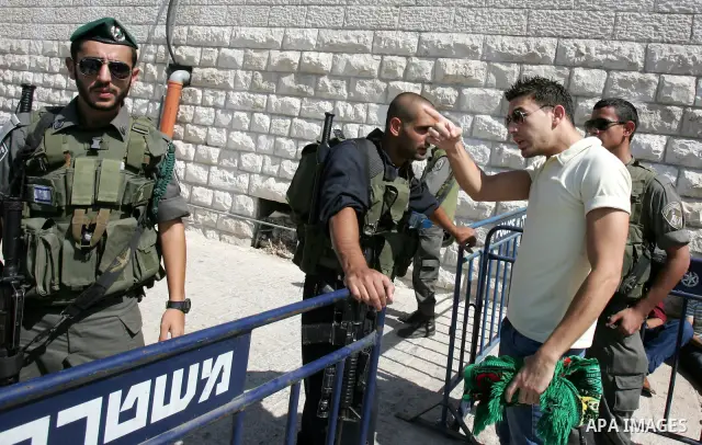 Israeli soldiers stand guard as Palestinian Muslims attend Friday prayers at a street in the neighbourhood of Ras al-Amud, in East Jerusalem (Al-Aqsa Mosque compound in the background) on October 7,2011. Israel limited a...