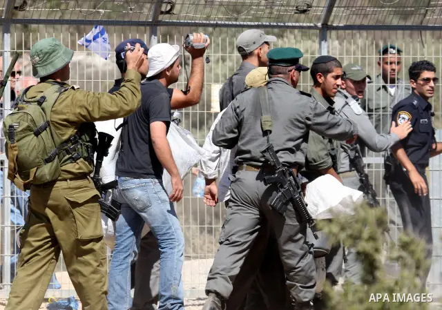 Jewish settlers from the Itamar settlement are moved along by Israeli soldiers after they clashed with Palestinian farmers from the village of Awarta in the Israeli occupied West Bank, on October 9, 2011, as they tried t...