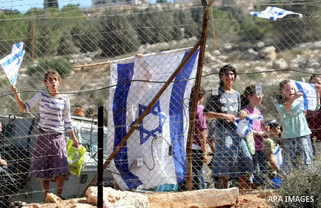 Jewish settlers from the Itamar settlement wave the Israeli flag after settlers clashed with Palestinian farmers from the village of Awarta in the Israeli occupied West Bank, on October 9, 2011, as they tried to pick oli...