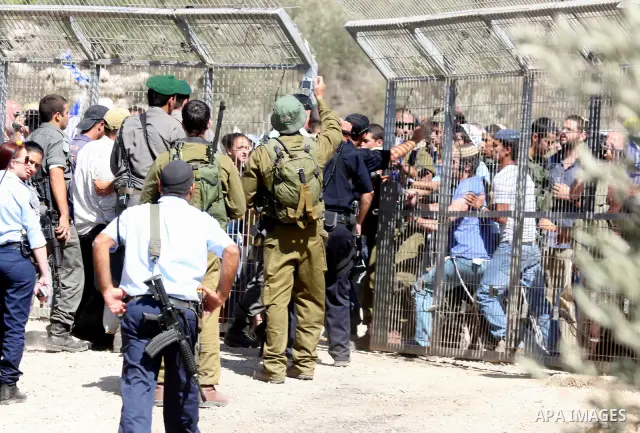 Jewish settlers from the Itamar settlement are moved along by Israeli soldiers after they clashed with Palestinian farmers from the village of Awarta in the Israeli occupied West Bank, on October 9, 2011, as they tried t...