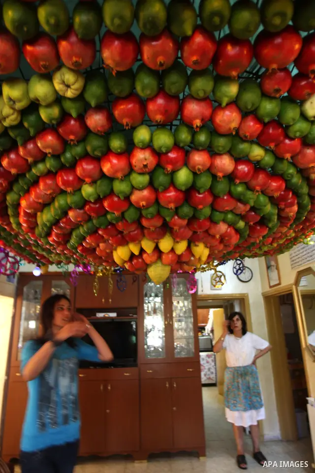 A woman from the ancient Samaritan community decorates a Sukkah made from fresh fruit for the holiday of the Tabernacles, or Sukkot, in Mount Gerizim near the West Bank town of Nablus, Monday, Oct. 10, 2011. The Sukkah i...