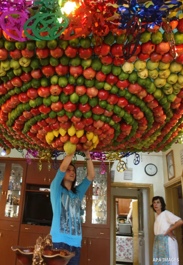 A woman from the ancient Samaritan community decorates a Sukkah made from fresh fruit for the holiday of the Tabernacles, or Sukkot, in Mount Gerizim near the West Bank town of Nablus, Monday, Oct. 10, 2011. The Sukkah i...