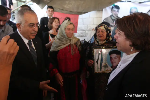 Palestinian prime minister Salam Fayyad sits with relatives of Palestinian prisoners who are held in Israeli jails in a protest tent build in front of the Red Cross' offices in the West Bank city of Ramallah, on October...