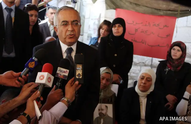 Palestinian prime minister Salam Fayyad sits with relatives of Palestinian prisoners who are held in Israeli jails in a protest tent build in front of the Red Cross' offices in the West Bank city of Ramallah, on October...