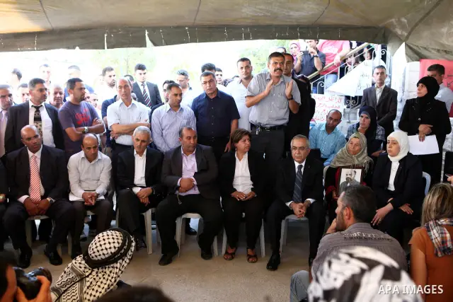 Palestinian prime minister Salam Fayyad sits with relatives of Palestinian prisoners who are held in Israeli jails in a protest tent build in front of the Red Cross' offices in the West Bank city of Ramallah, on October...