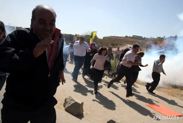 Palestinian protestors run for cover as Israeli forces fire tear gas canisters during clashes following a demonstration calling for the release of prisoners held in Israeli jails and in support of inmates in hunger strik...