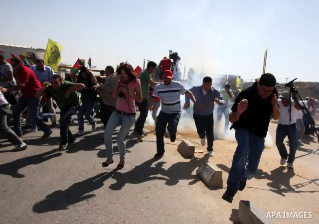 Palestinian protestors run for cover as Israeli forces fire tear gas canisters during clashes following a demonstration calling for the release of prisoners held in Israeli jails and in support of inmates in hunger strik...
