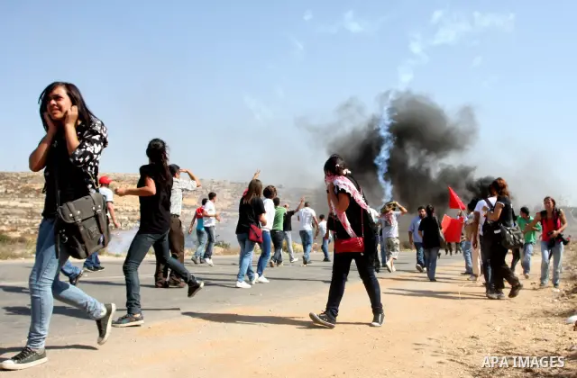 Palestinian protestors run for cover as Israeli forces fire tear gas canisters during clashes following a demonstration calling for the release of prisoners held in Israeli jails and in support of inmates in hunger strik...