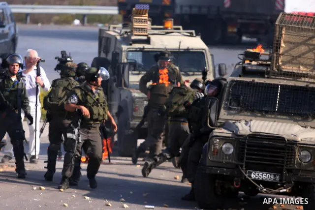 An Israeli soldier sets ablaze by a molotov cocktail hurled by Palestinians during a demonstration calling for the release of prisoners held in Israeli jails and in support of inmates in hunger strike, on October 11, 201...